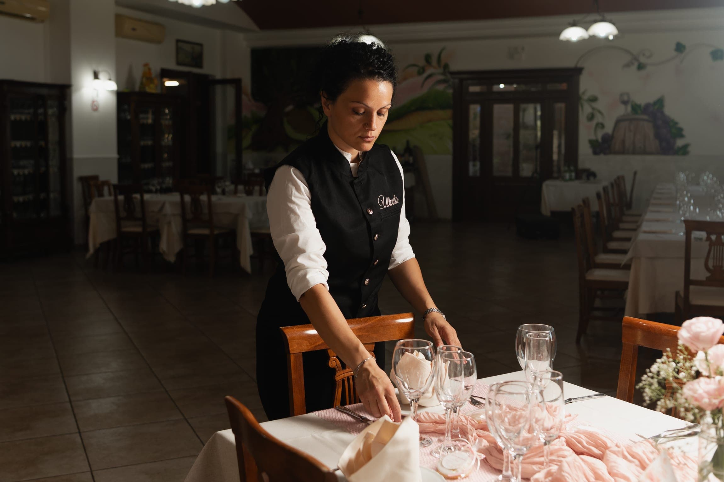 Una cameriera apparecchia un tavolo nella sala del ristorante della Tenuta L’Uliveto