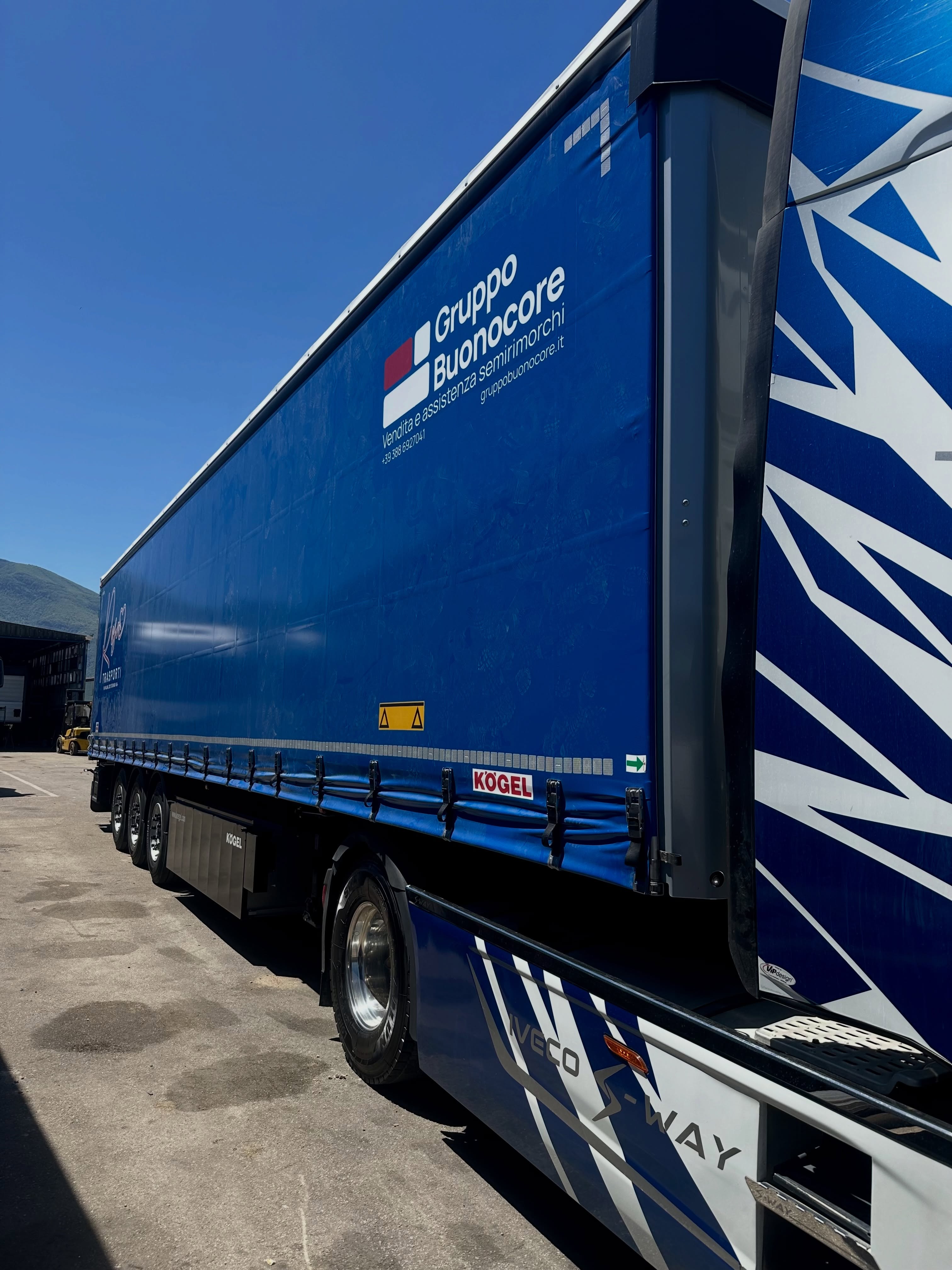Semirimorchio con telone blu e logo nel piazzale