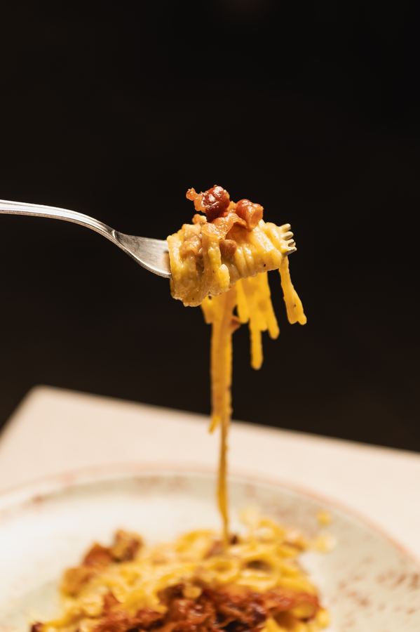Una ragazza assaggia un piatto di pasta